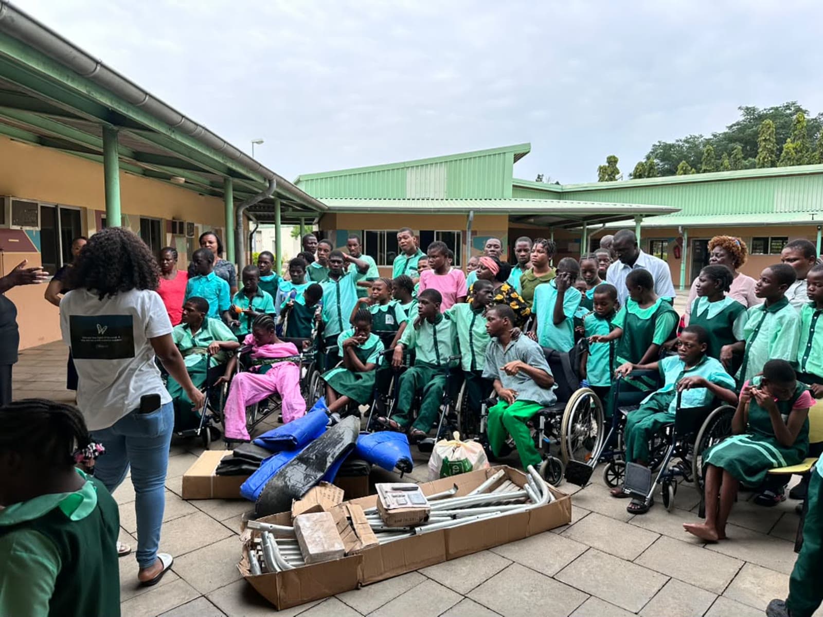 A philanthropist stands with pupils of the Model Centre, many in wheelchairs, beside the boxed trampoline she donated