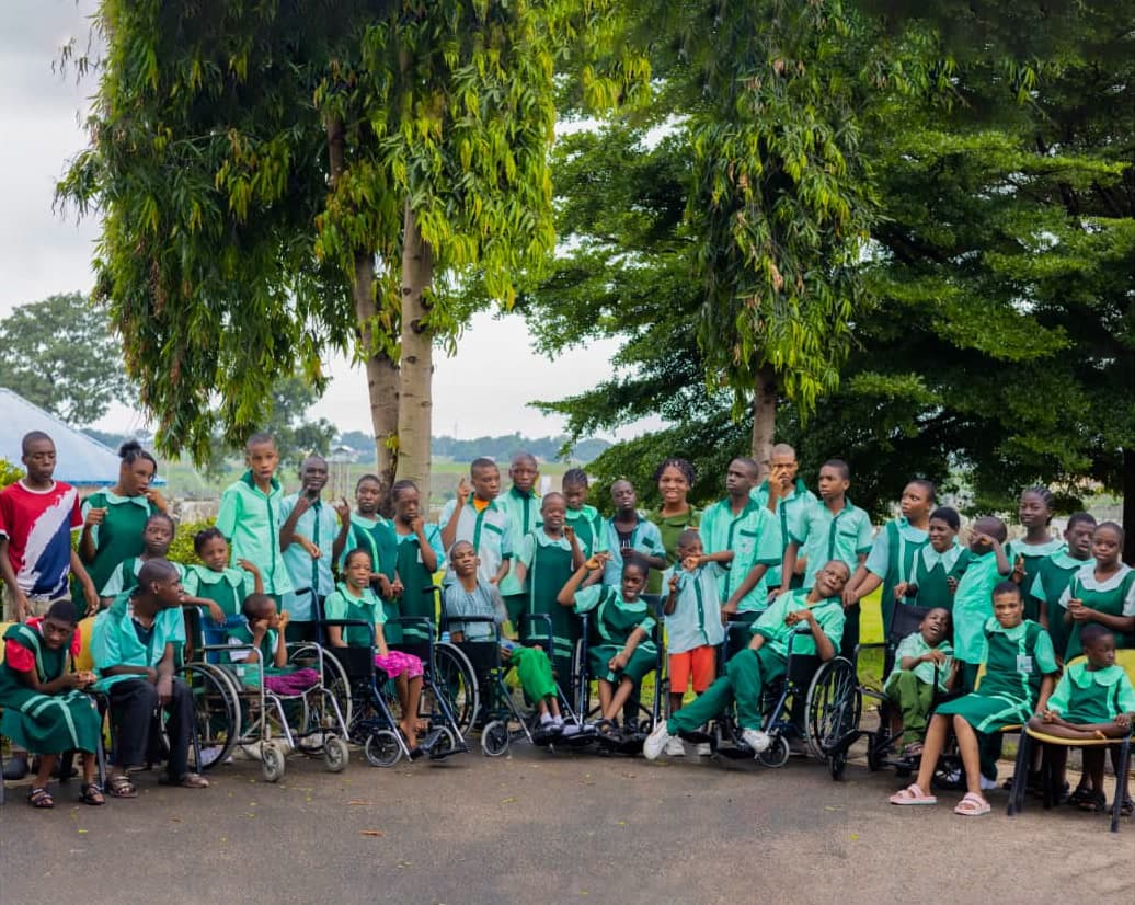 Pupils of Childcare Trust, many in wheelchairs, in green school uniforms under the trees at the Model Centre in Bwari